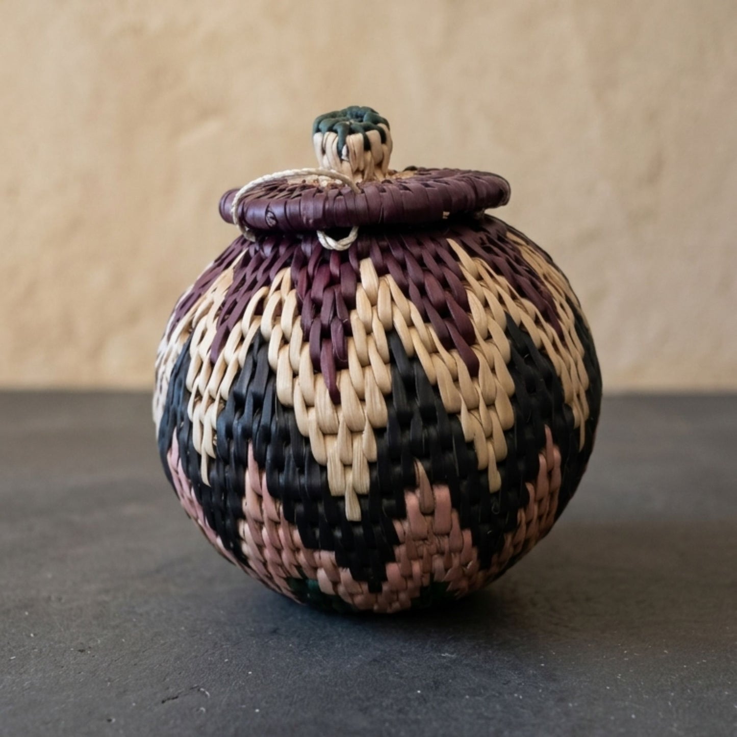 Woven basket with a lid on a dark surface and beige background