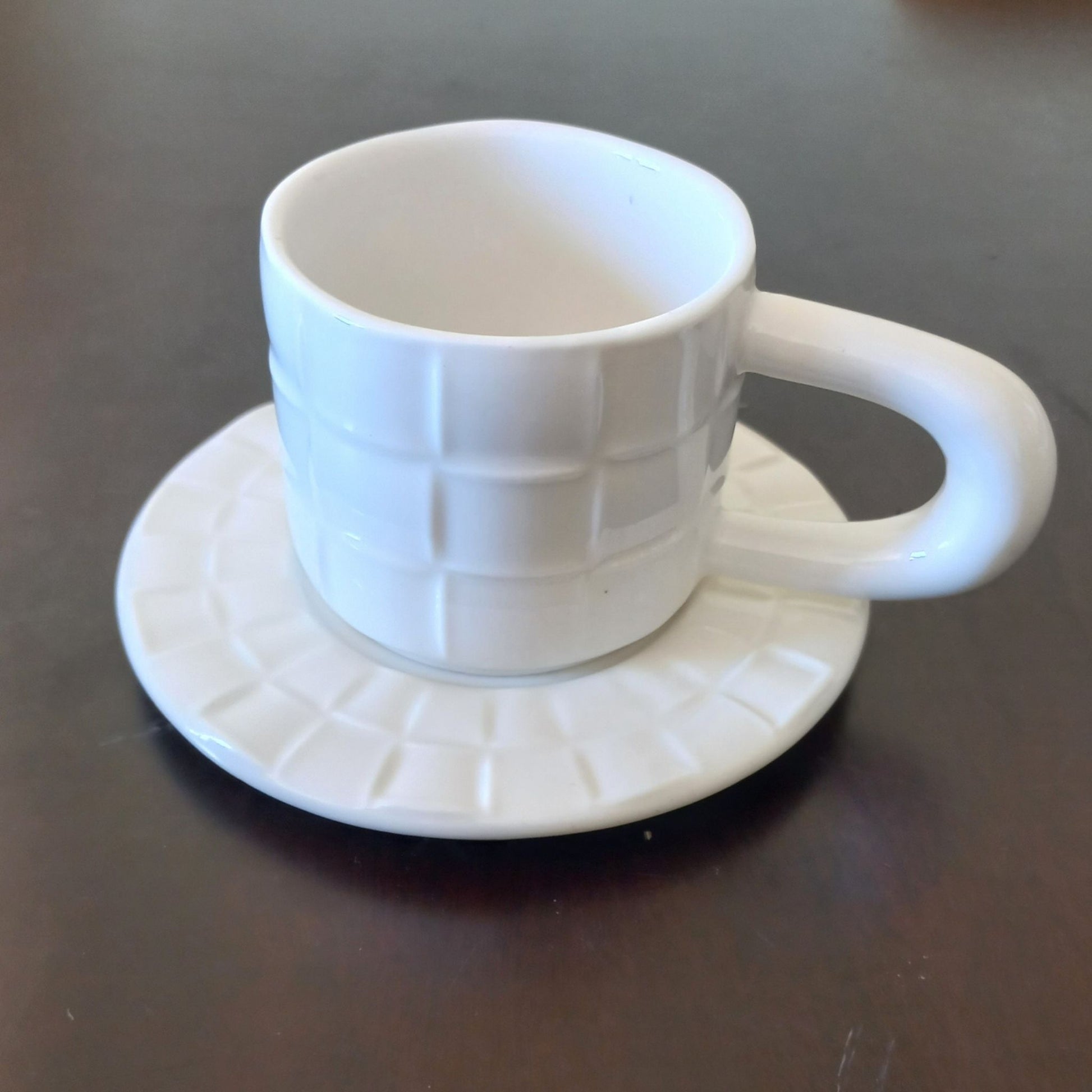 White textured cup and saucer on a dark surface