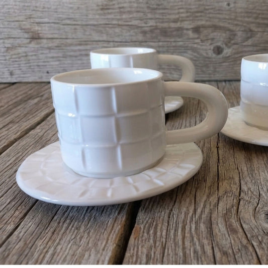White textured coffee cups with saucers on a wooden surface