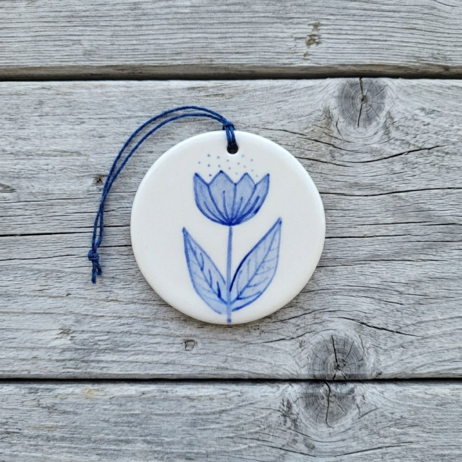 Round ceramic ornament with blue floral design on a wooden surface