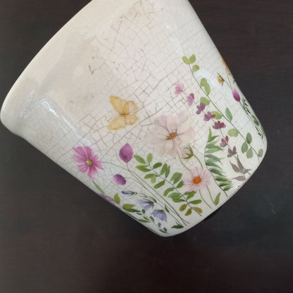 Ceramic mug with floral and butterfly design on a dark surface
