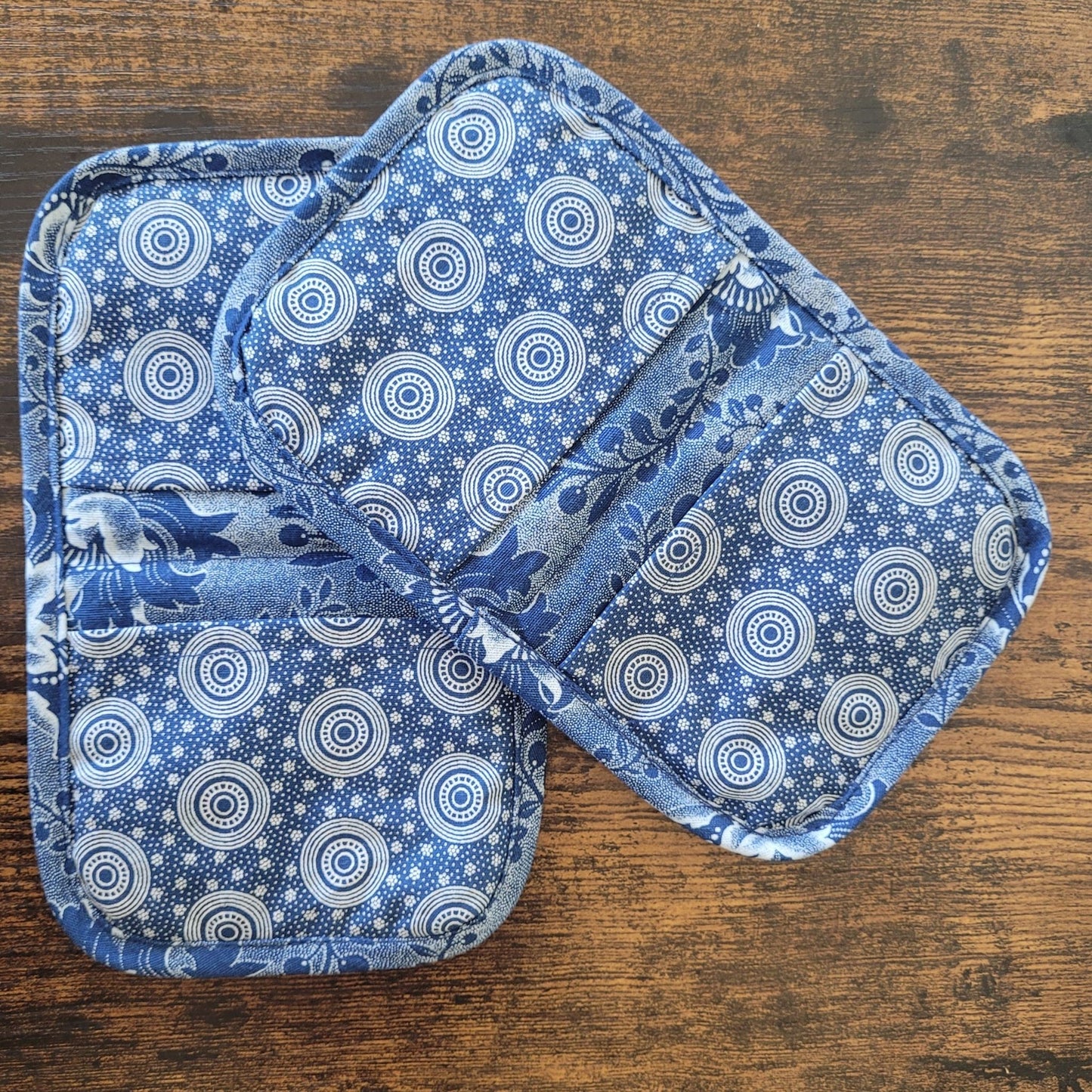 Two blue and white patterned pot holders on a wooden surface