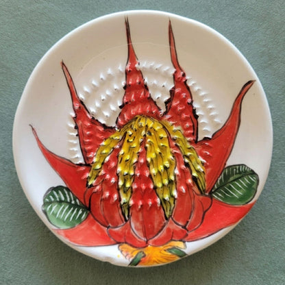 Ceramic grater plate with a red and yellow floral design on a green background