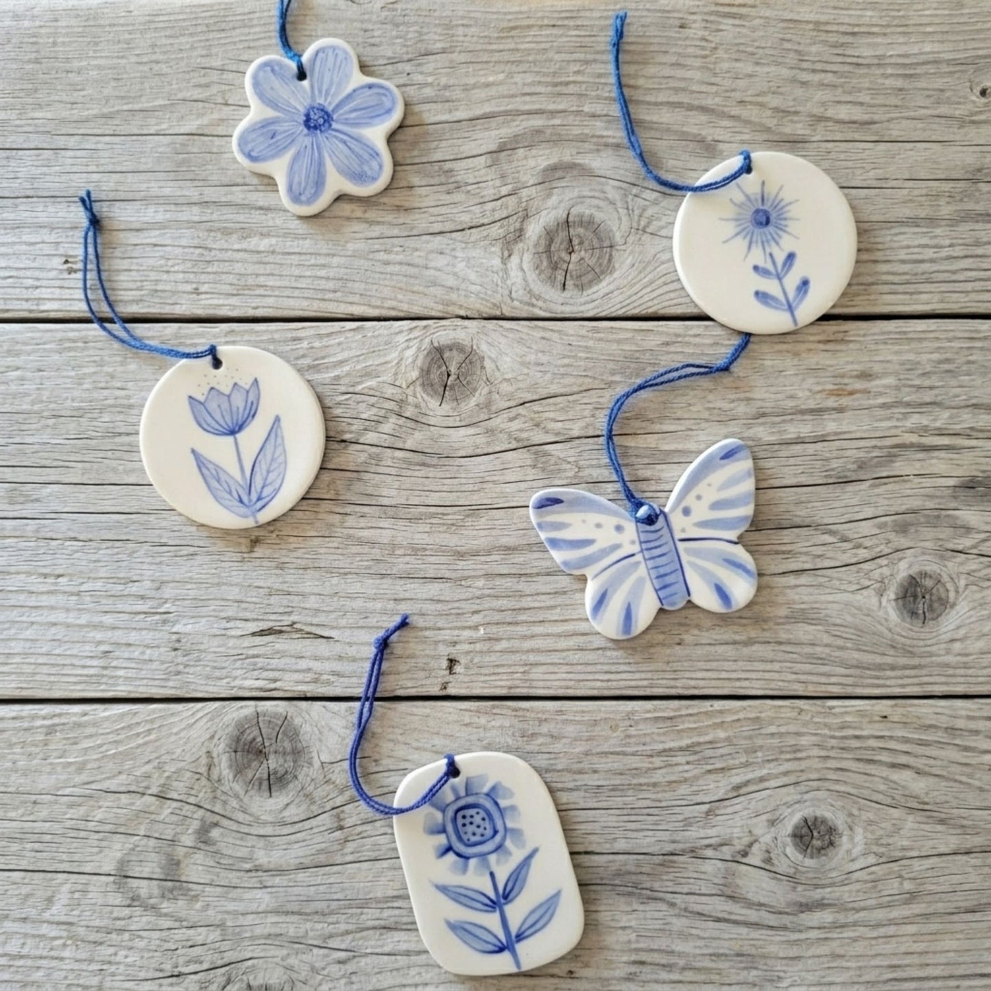 Decorative ceramic ornaments with floral and butterfly designs on a wooden surface