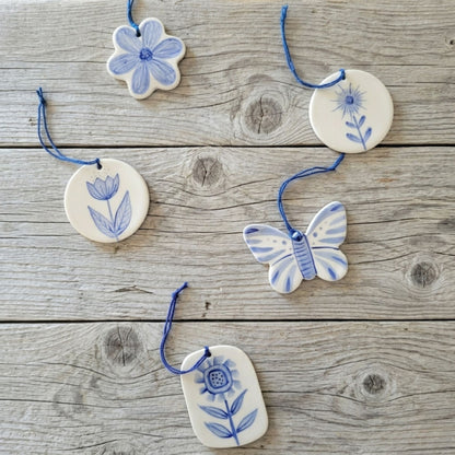 Decorative ceramic ornaments with floral and butterfly designs on a wooden surface
