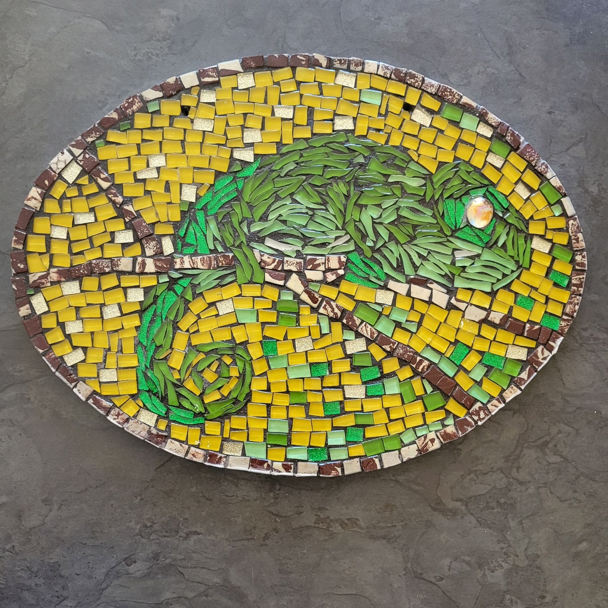 Mosaic artwork of a chameleon on a gray surface