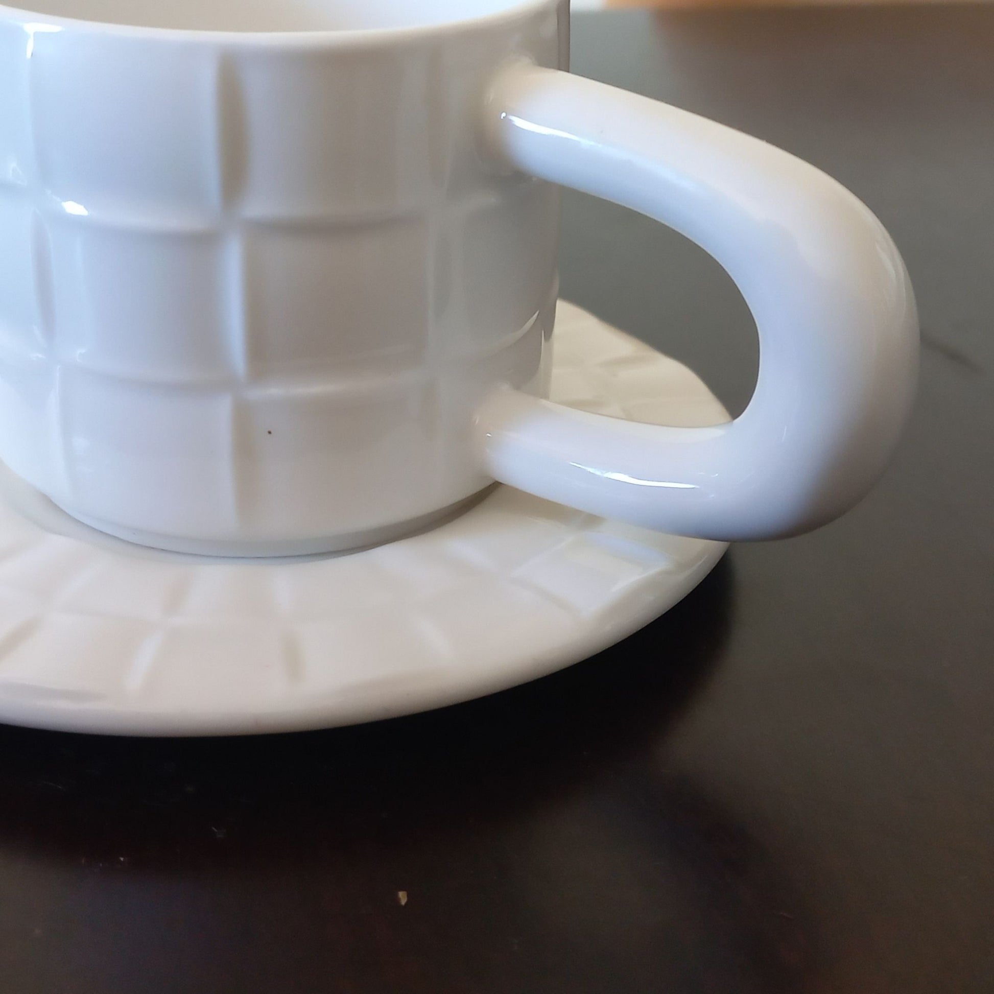 White ceramic cup and saucer on a dark surface