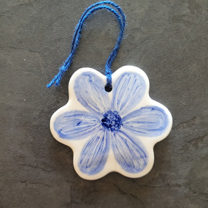 Ceramic flower ornament with blue floral design on a dark gray background