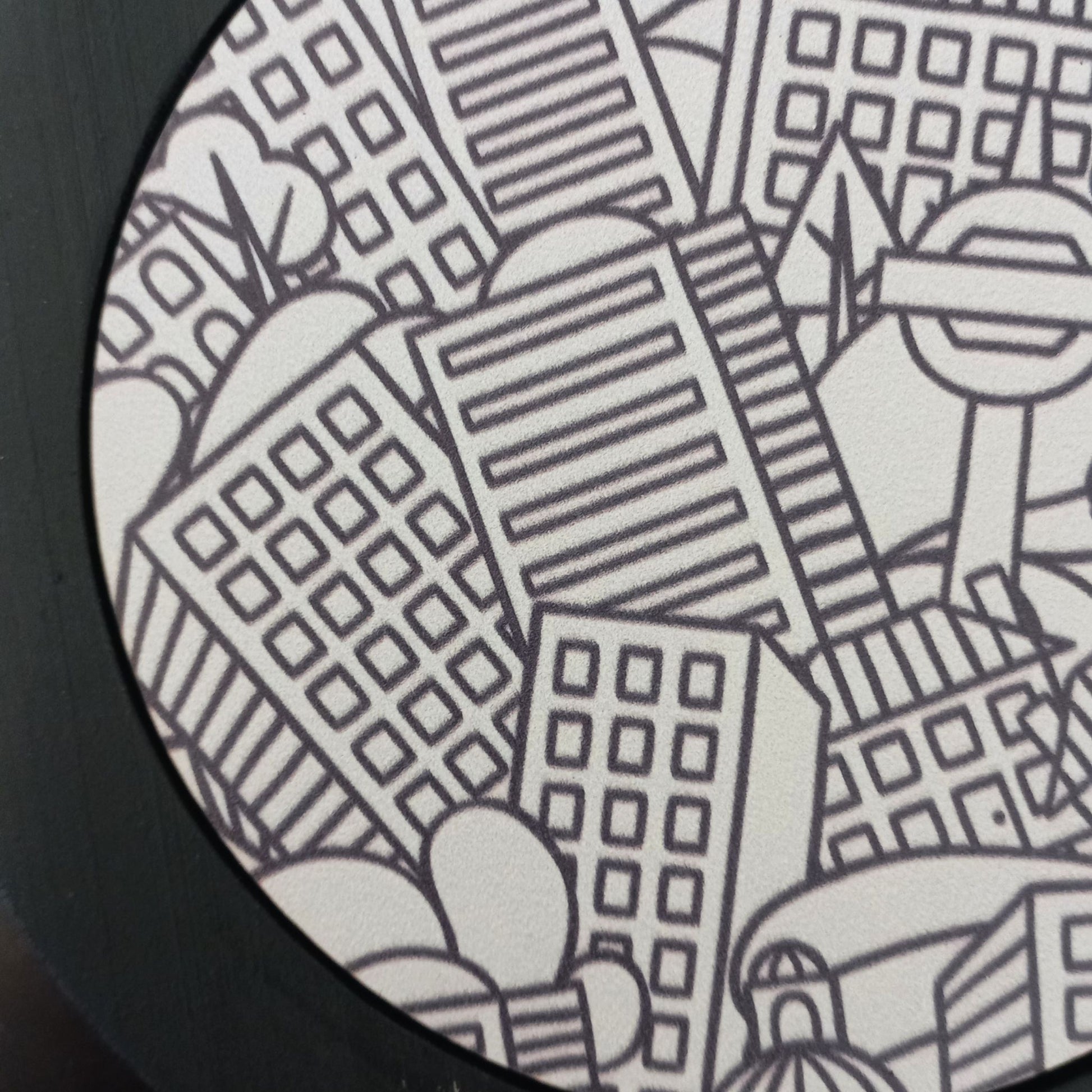 Black and white cut-out cityscape pot stand with buildings and trees on a circular background