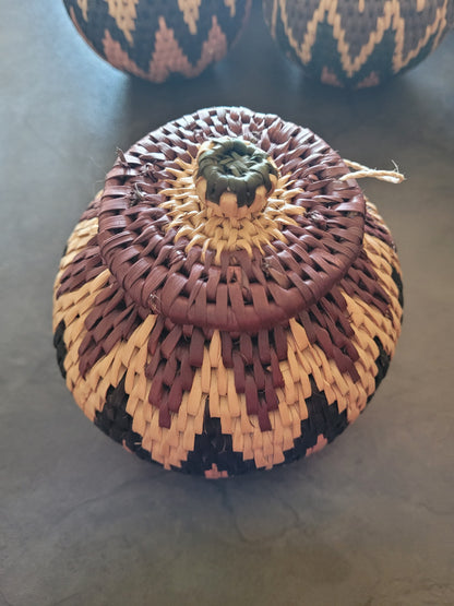 Woven zulu basket with a lid on a dark surface