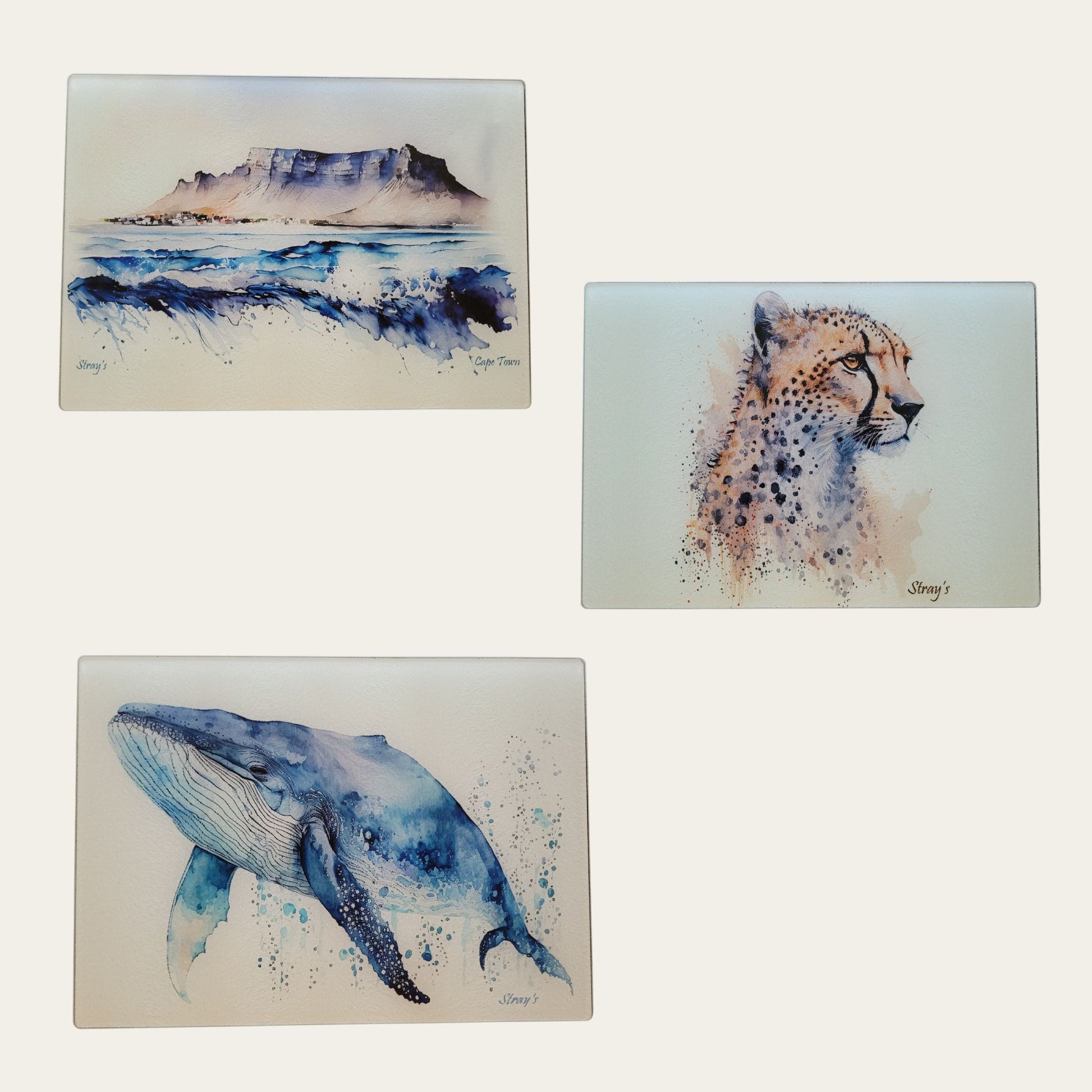 Three artistic illustrations of a mountain, cheetah, and whale glass cutting boards on a white background.