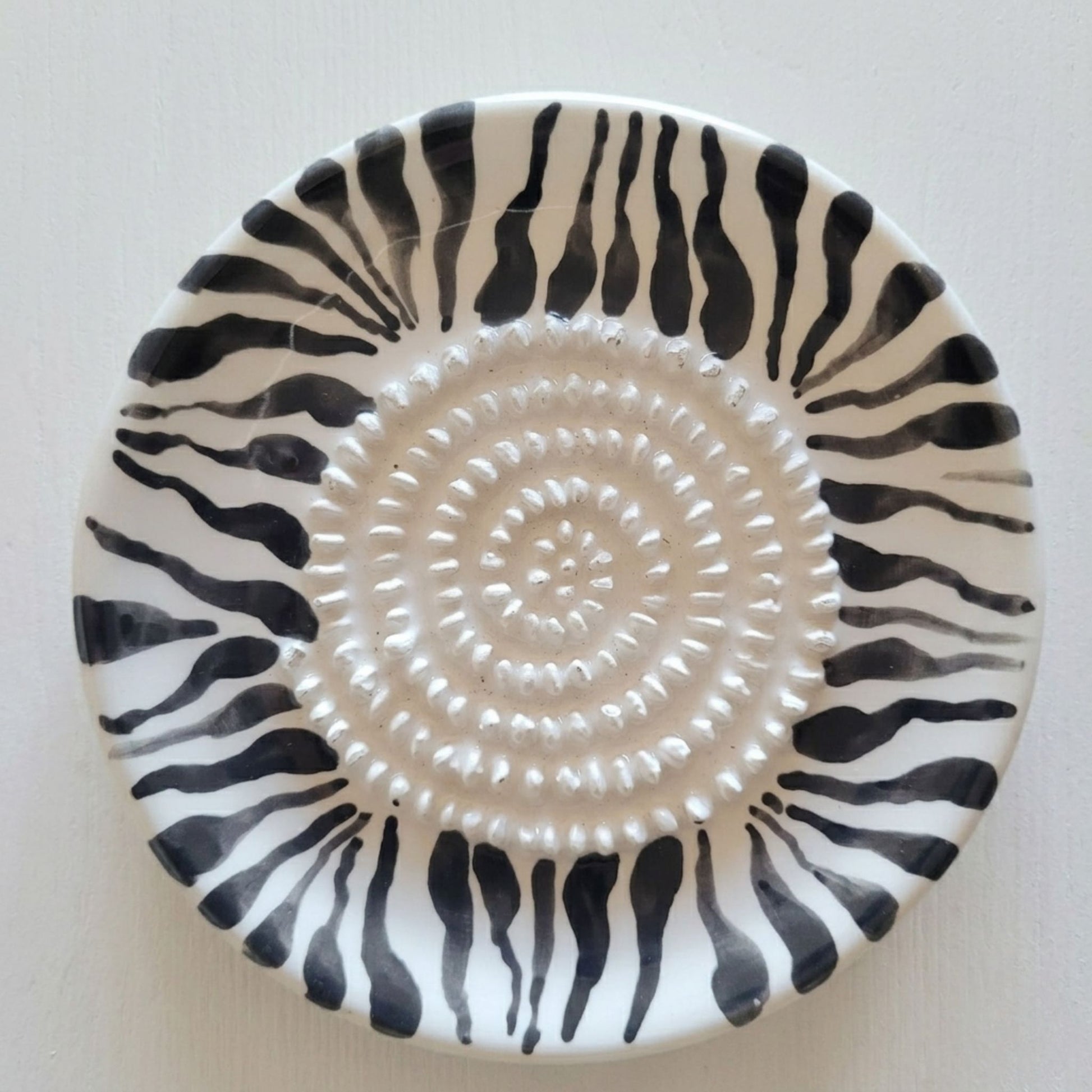 Ceramic grating plate with black and white zebra pattern on a white background