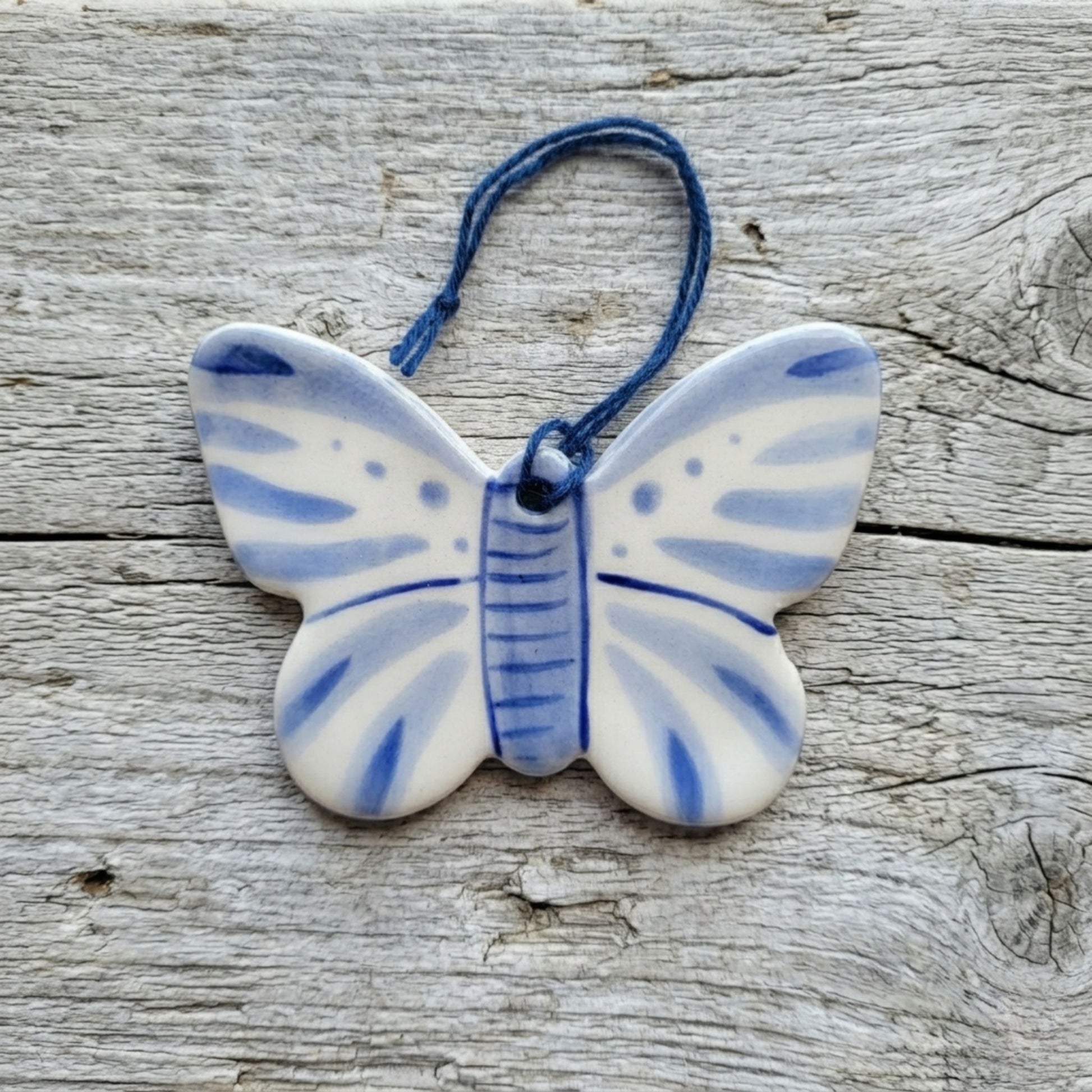 Ceramic butterfly ornament with blue and white pattern on a wooden surface