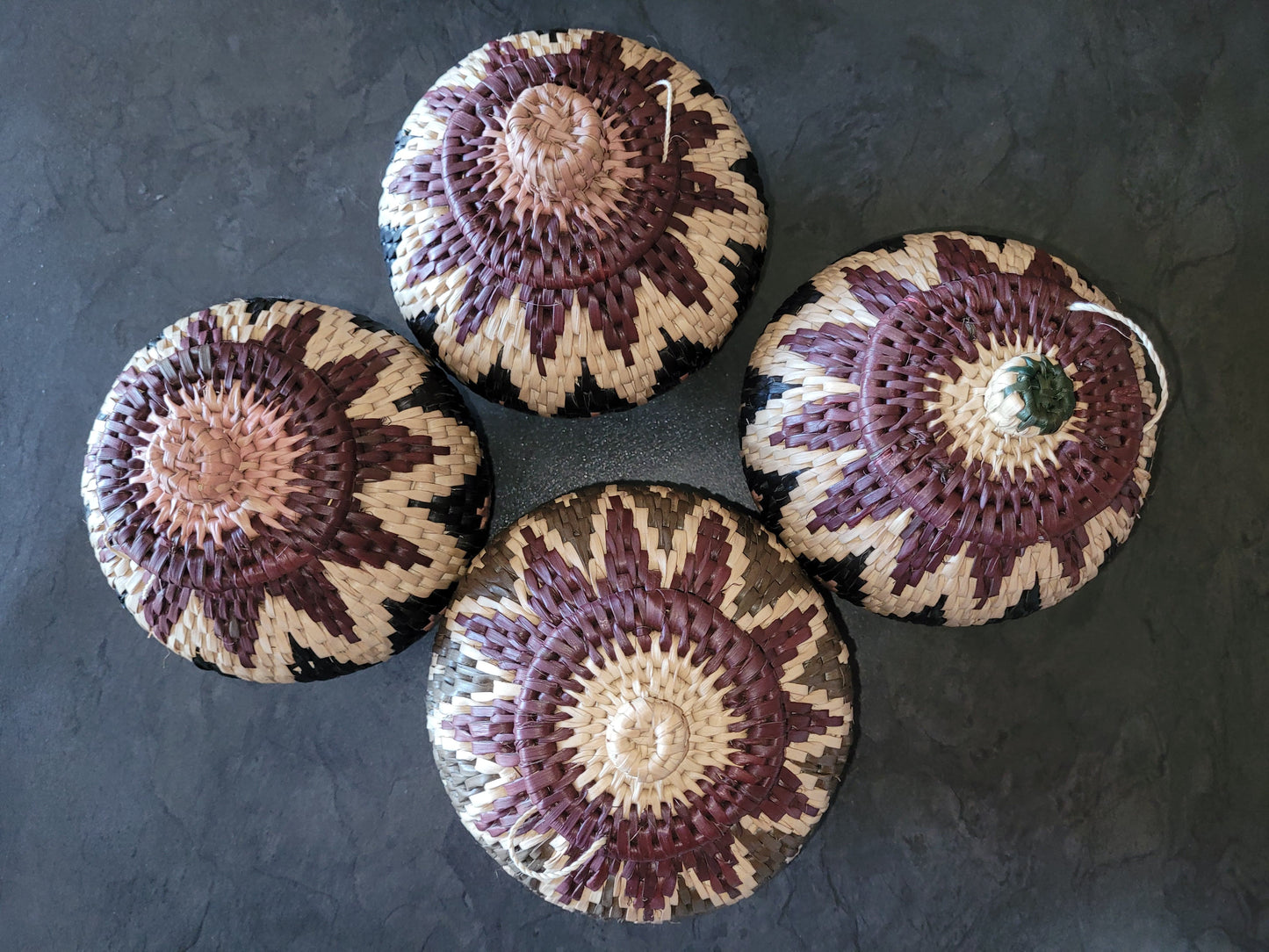 Four woven baskets with a circular pattern on a dark surface