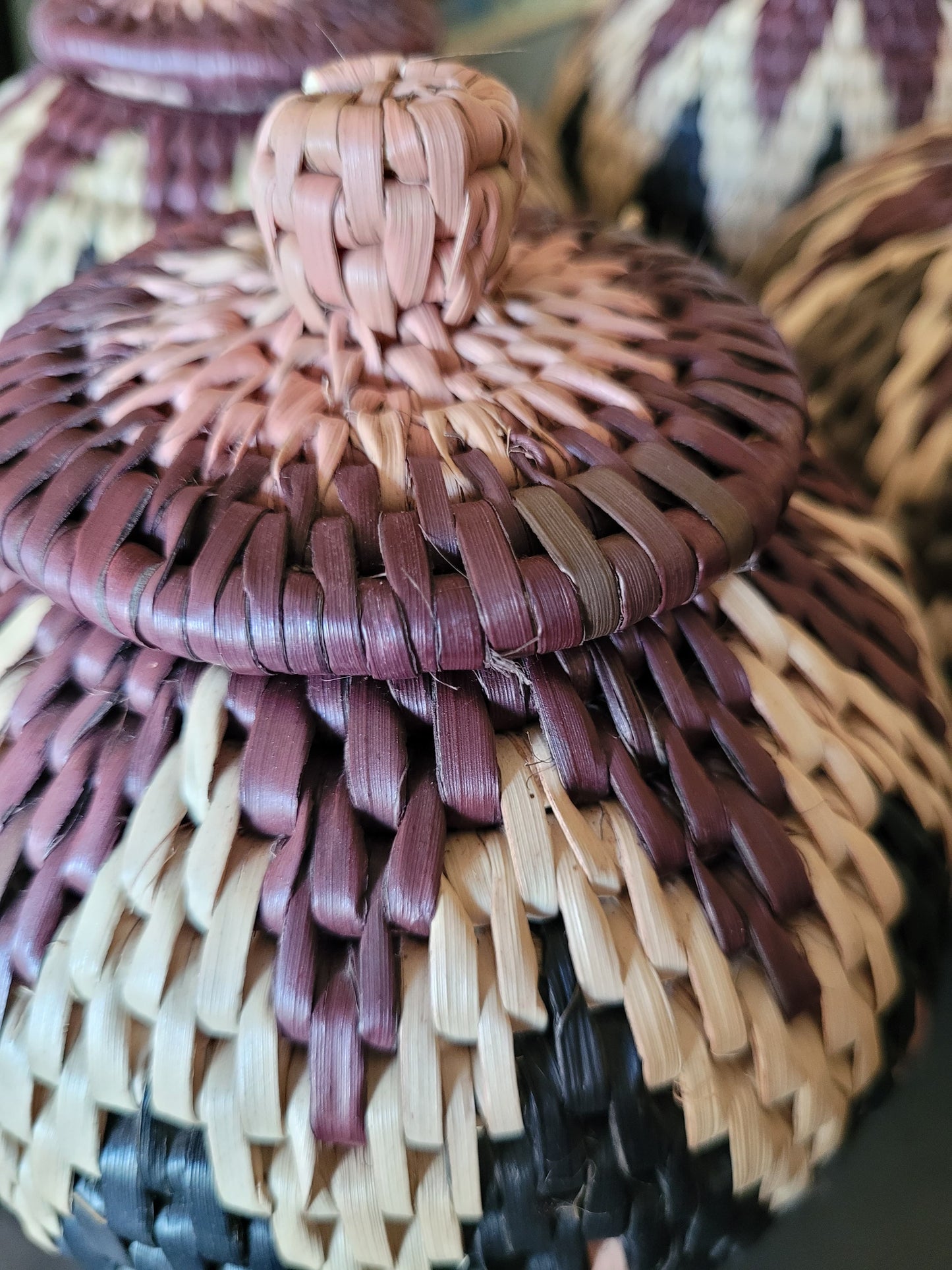 Close-up of a woven basket with a lid in various colors.