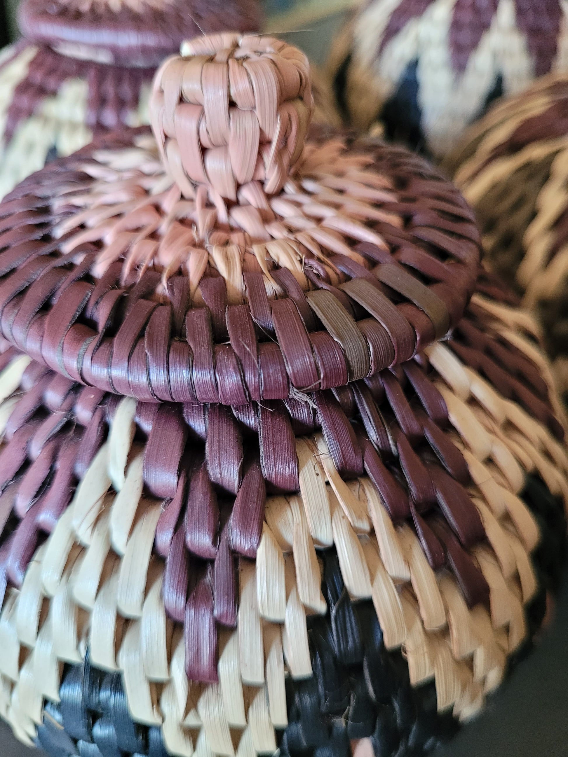 Close-up of a woven basket with a lid in various colors.