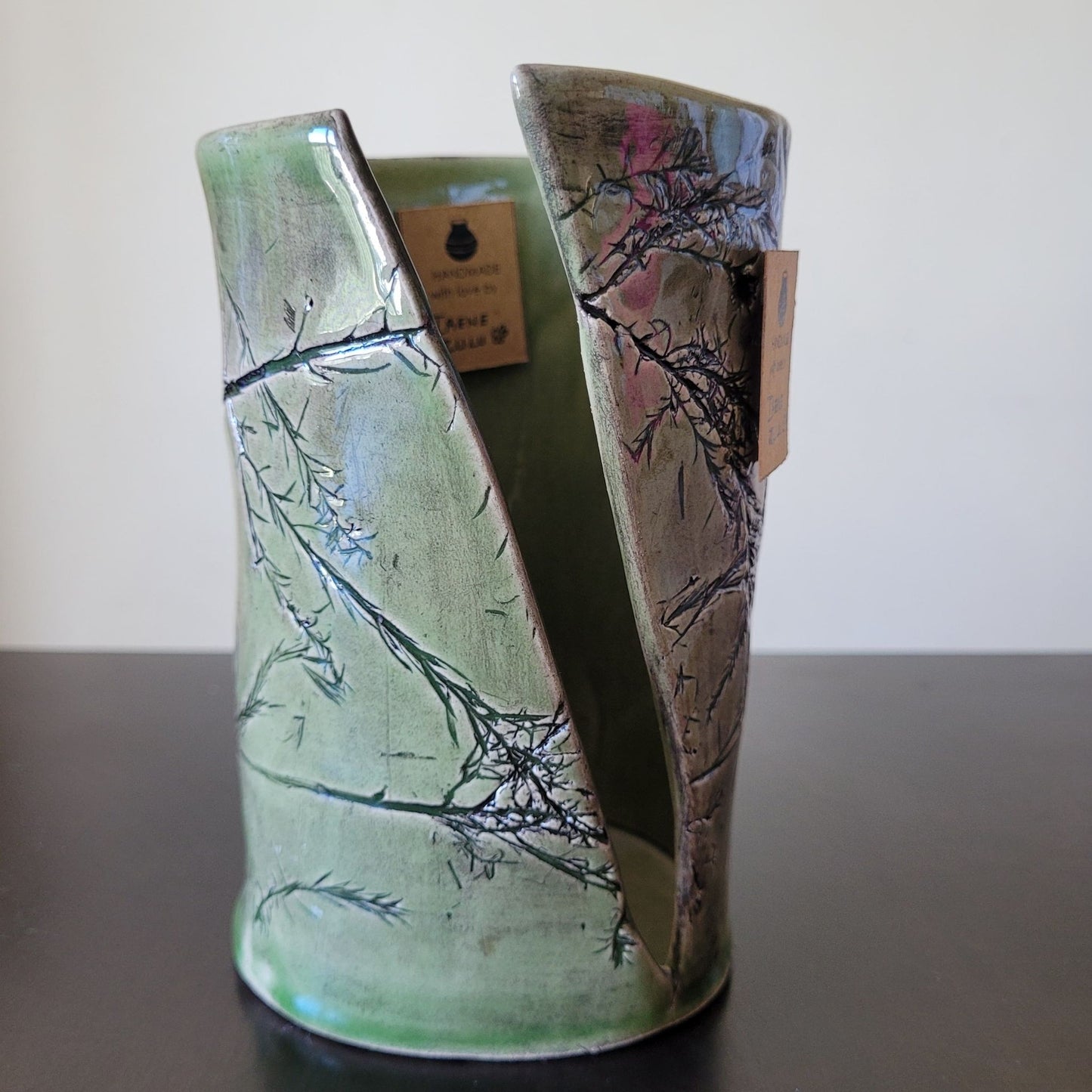 Ceramic vase with leafy imprinted design on a gray surface