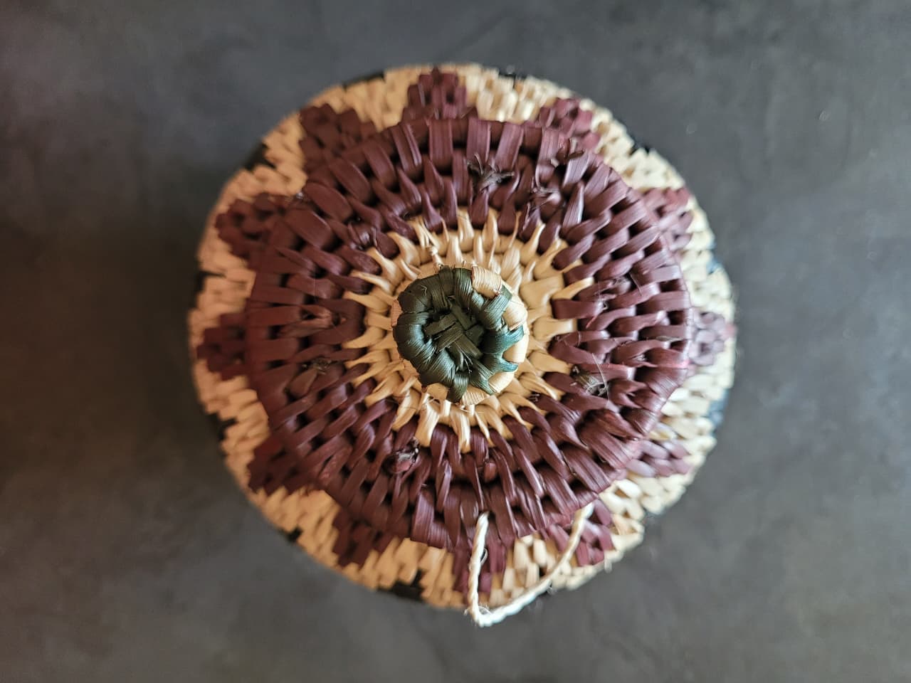 Decorative woven basket with concentric patterns on a dark surface