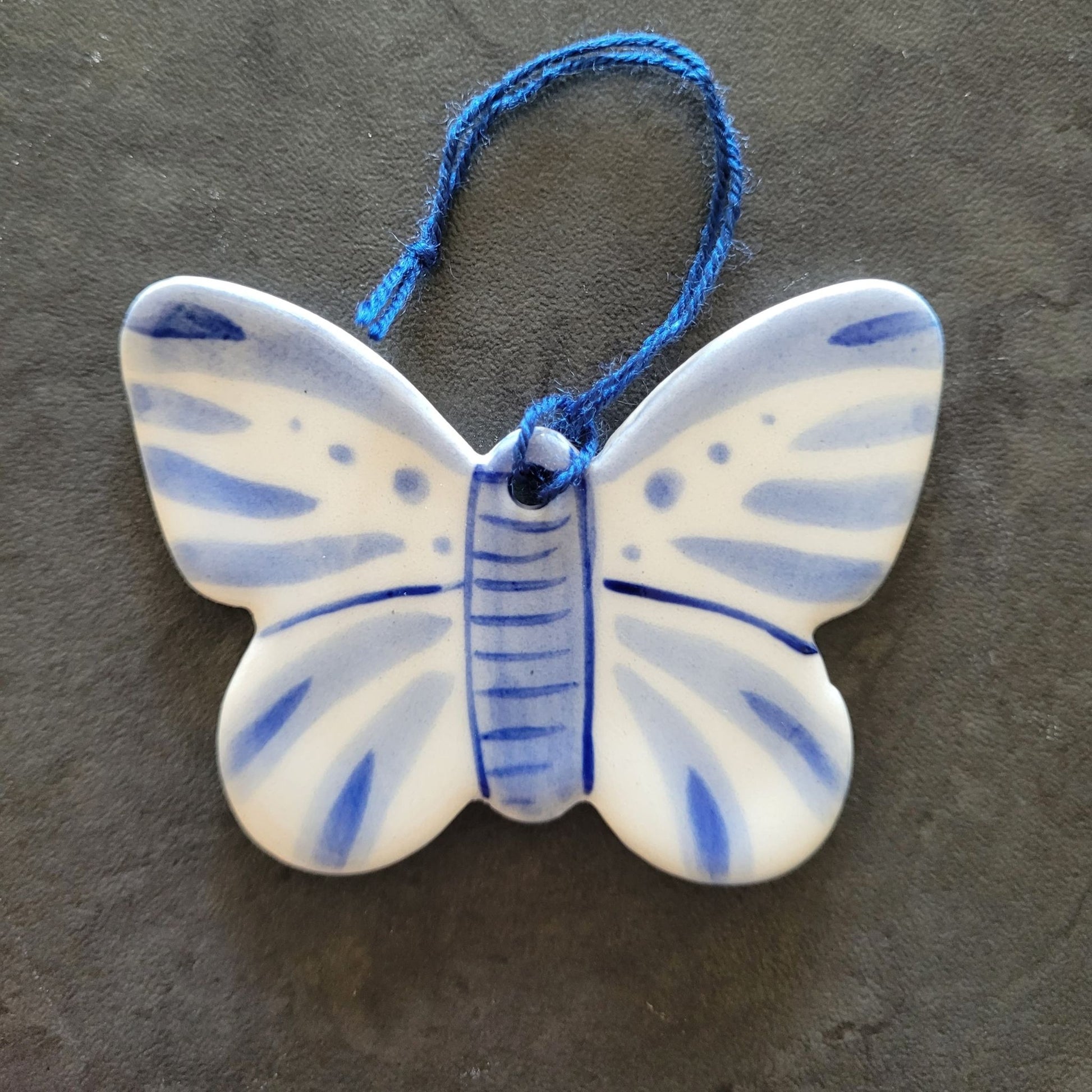 Ceramic butterfly ornament with blue and white design on a dark surface