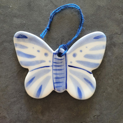 Ceramic butterfly ornament with blue and white design on a dark surface