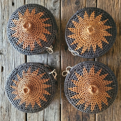 Four woven African baskets with starburst patterns on a wooden surface