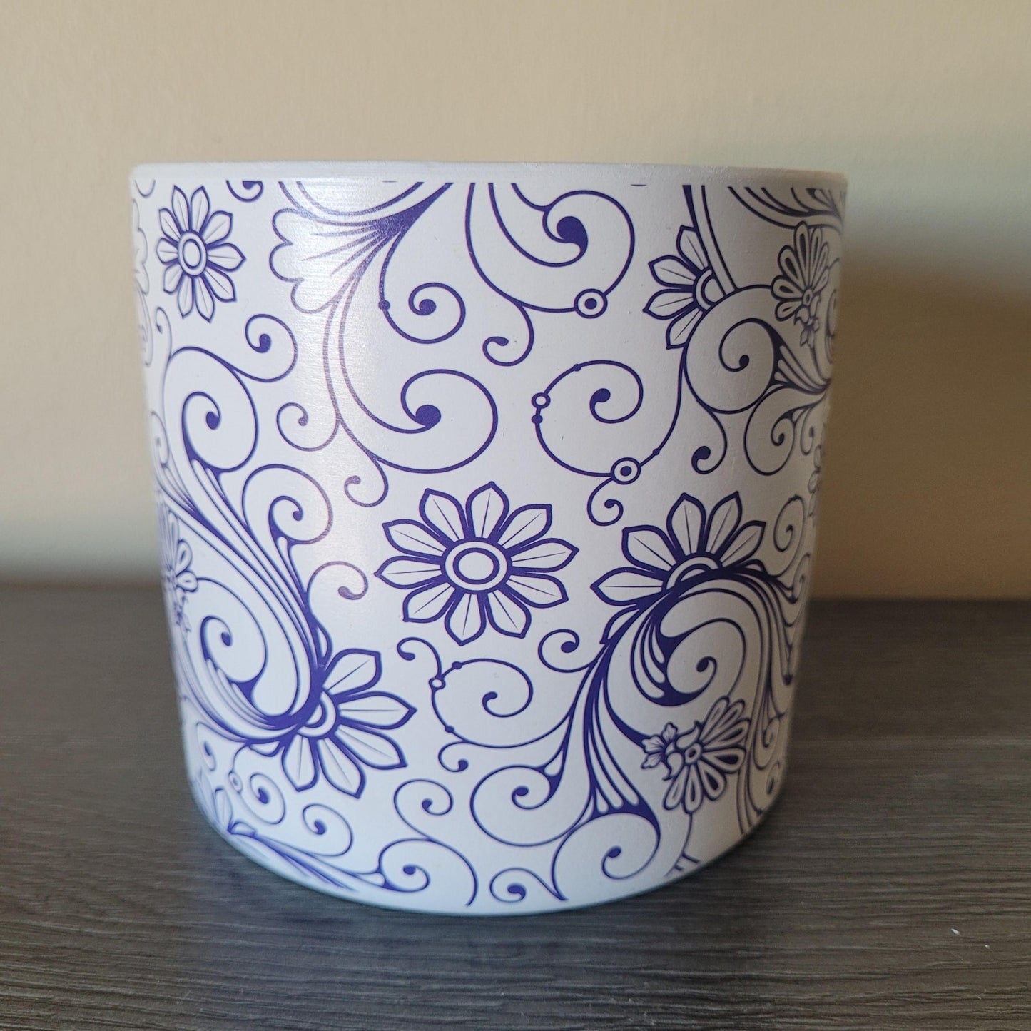 Ceramic plant pot with blue floral and swirl patterns on a wooden surface.