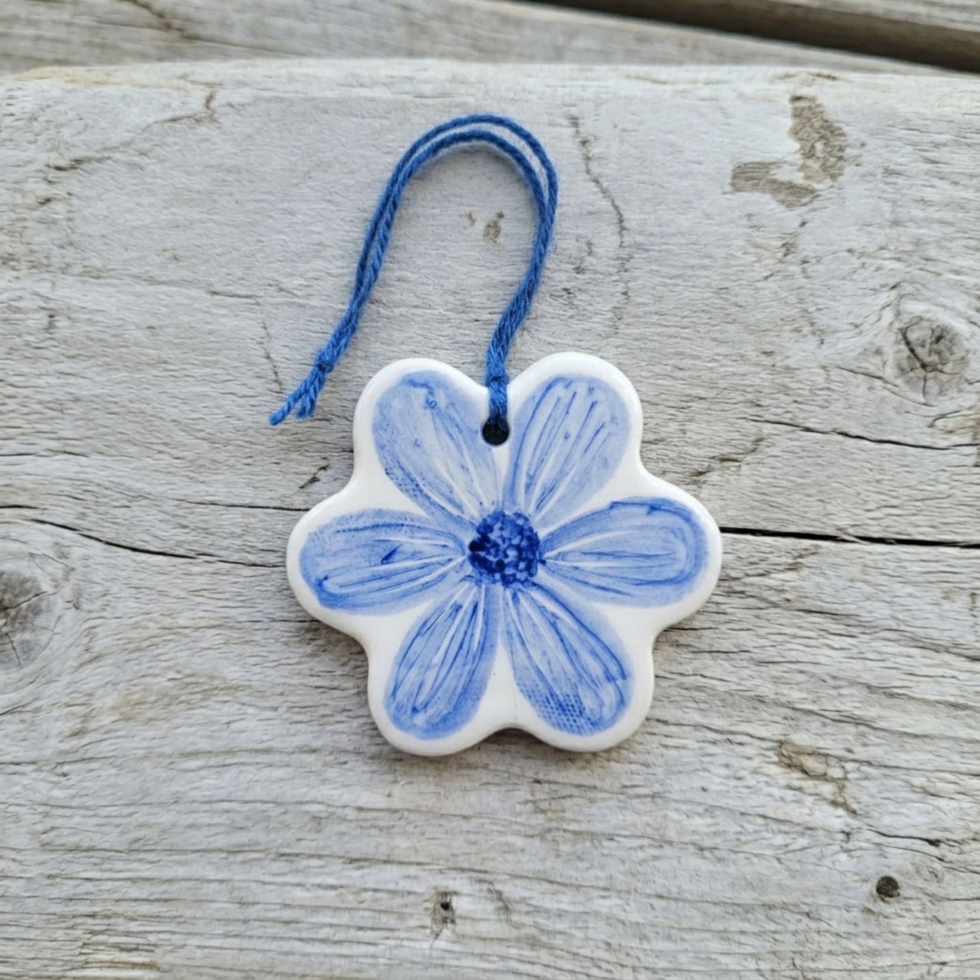 Decorative ceramic flower ornament with blue floral design on a wooden surface