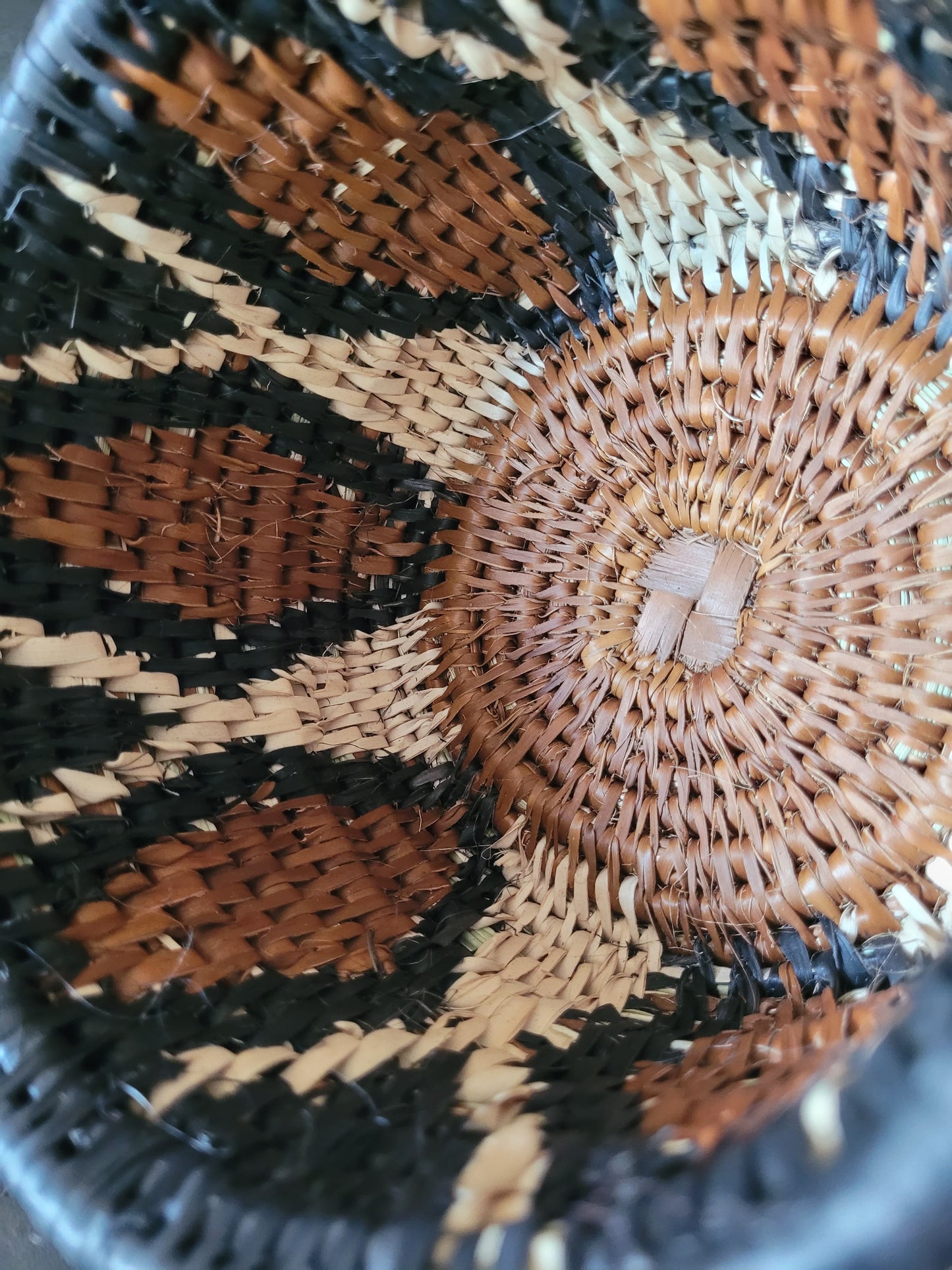 Close-up of a woven basket with intricate patterns in black, brown, and beige.