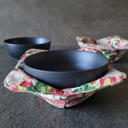 Black bowl in a colorful fabric bowl cozy with another bowl in the background.