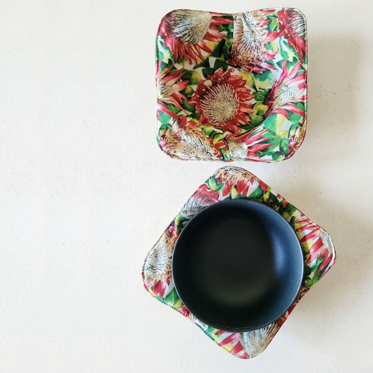Two floral-patterned bowl cozies with a black bowl on a white background