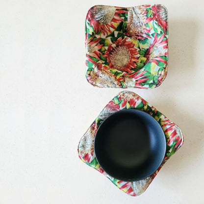 Two floral-patterned bowl cozies with a black bowl on a white background