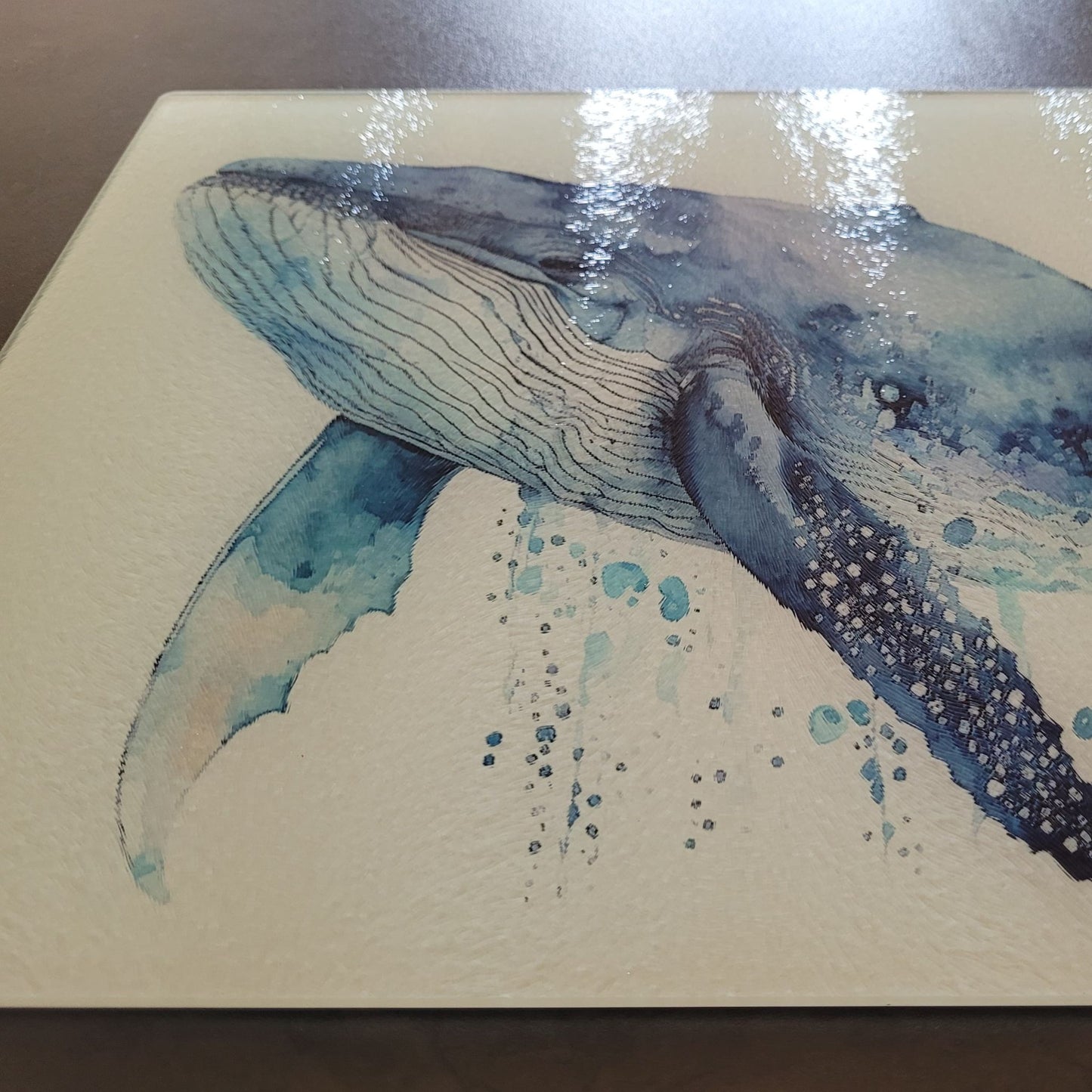 Glass cutting board of a whale on gray surface.