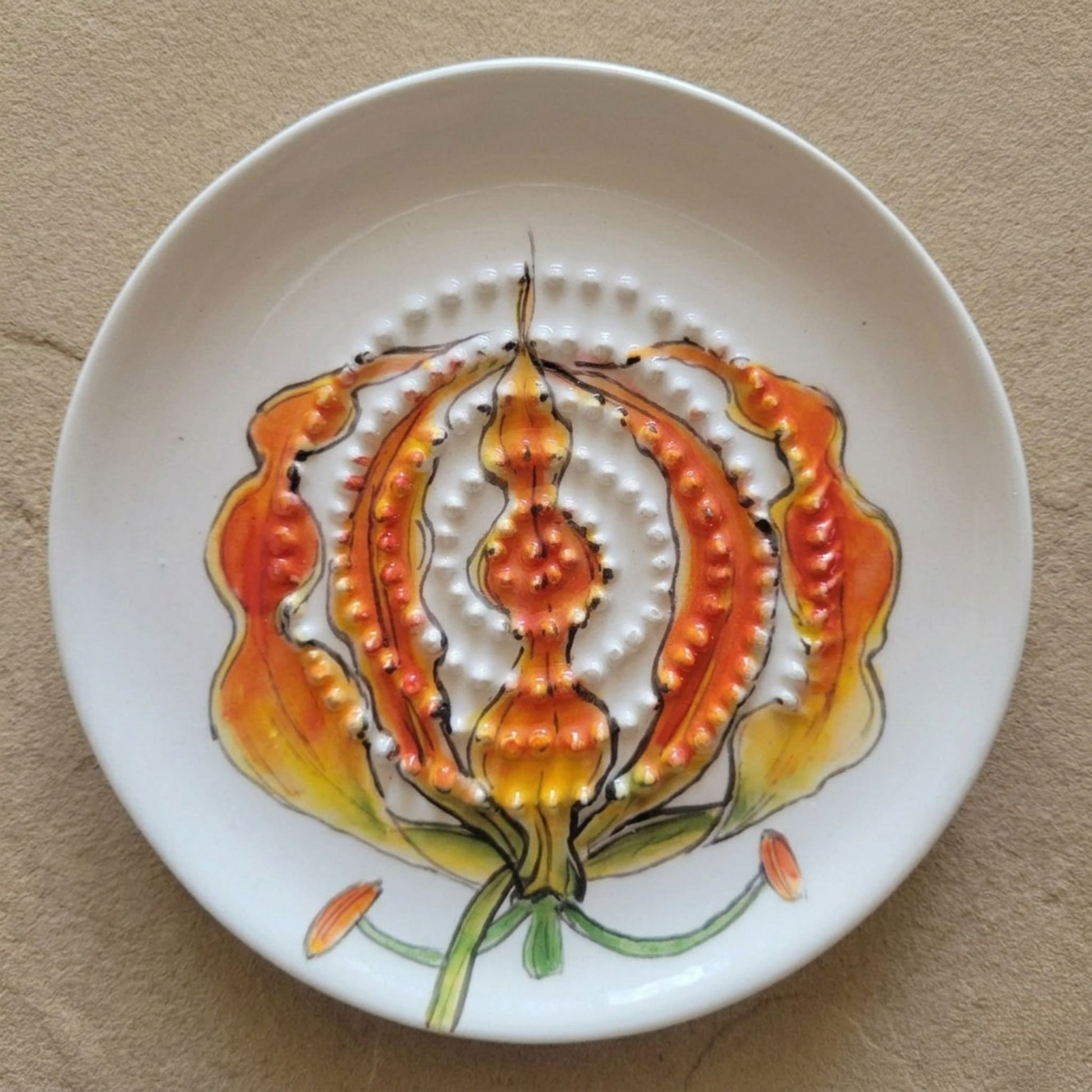 Ceramic grater plate with floral design on a beige surface