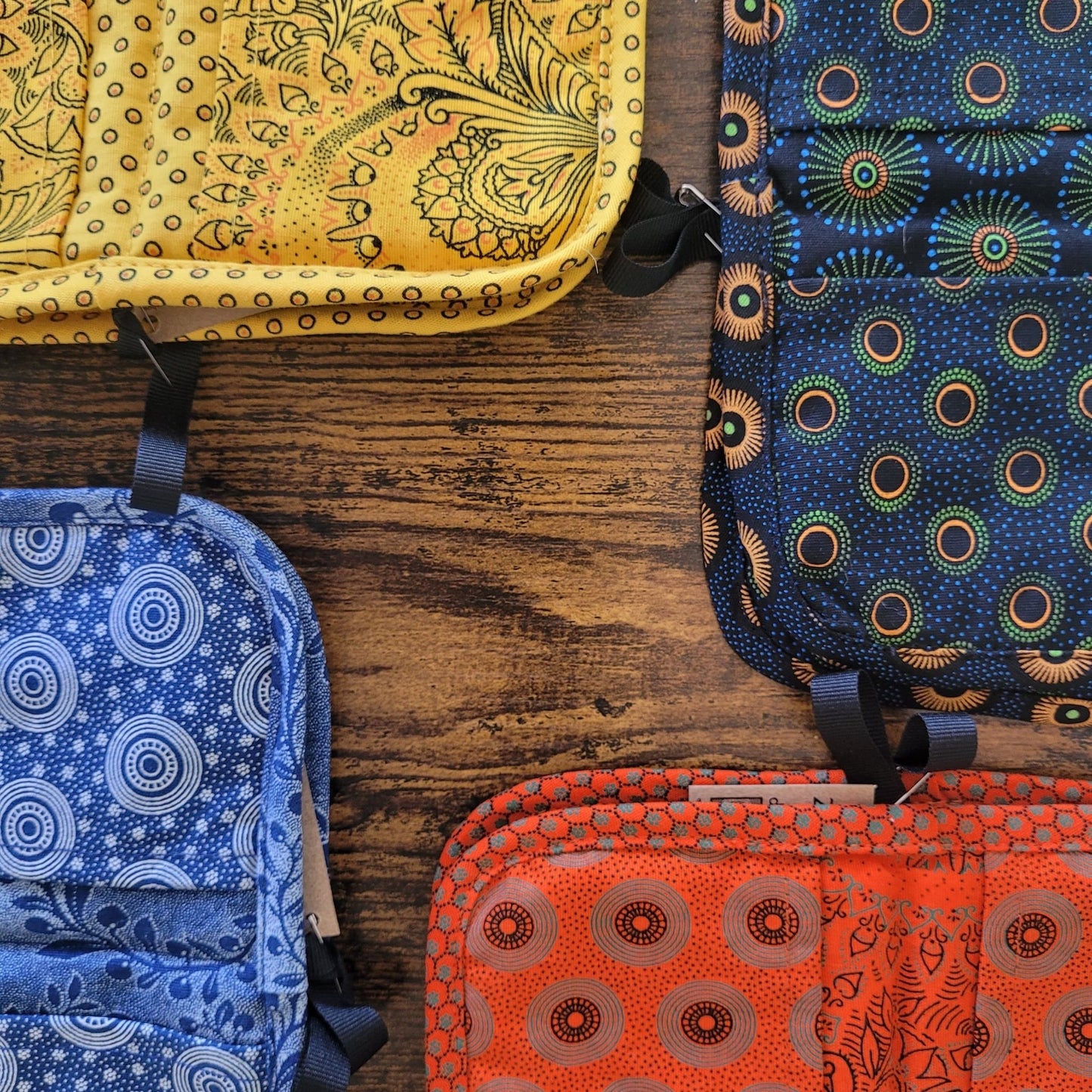 Four shweshwe pot holders on a wooden surface