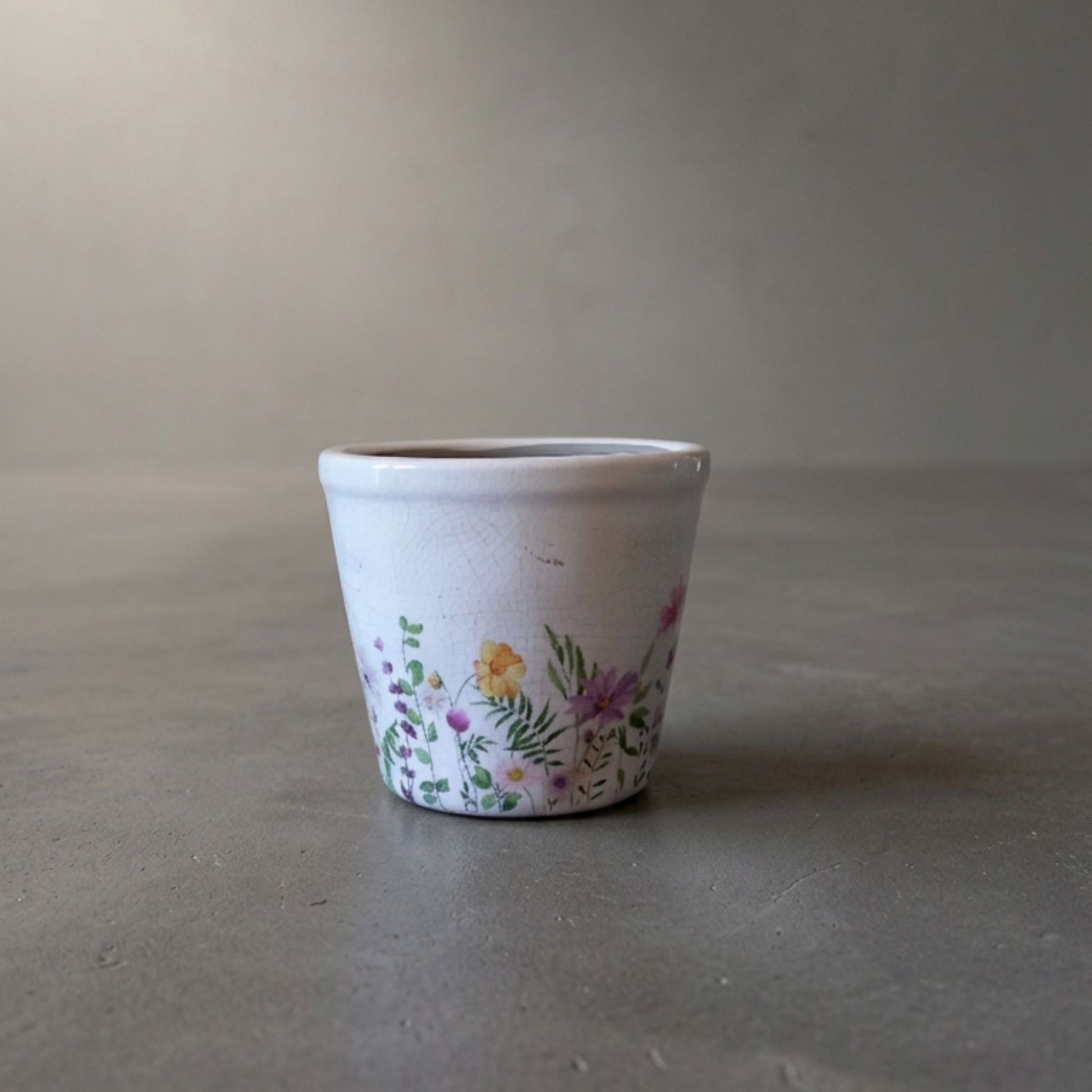 Small ceramic pot with floral design on a gray surface